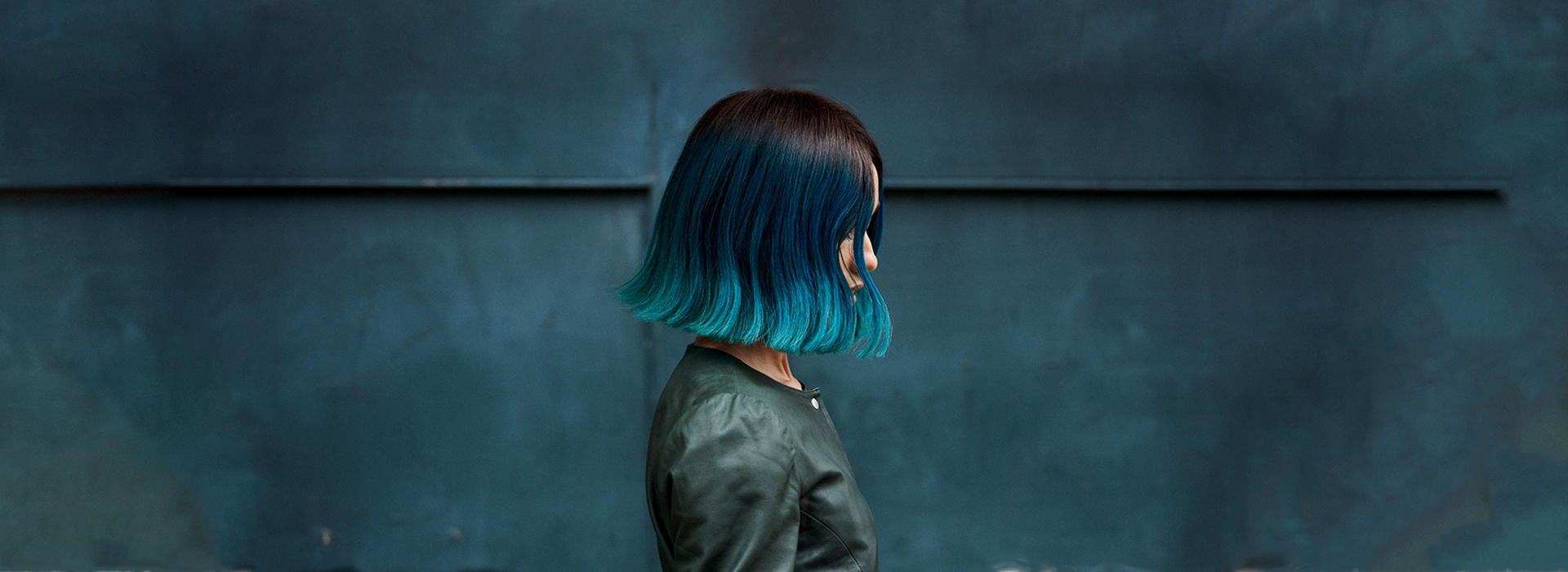 Woman with short hair. Hair color transitions from top to bottom as brown, blue and finally cyan